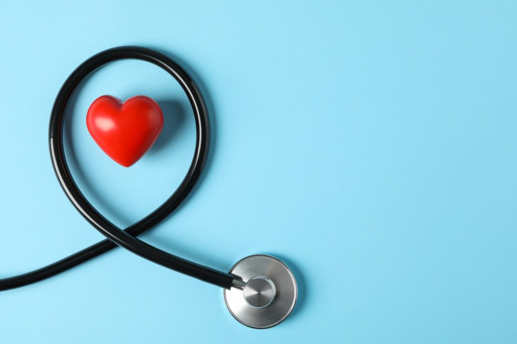 Stethoscope and heart on blue background, top view