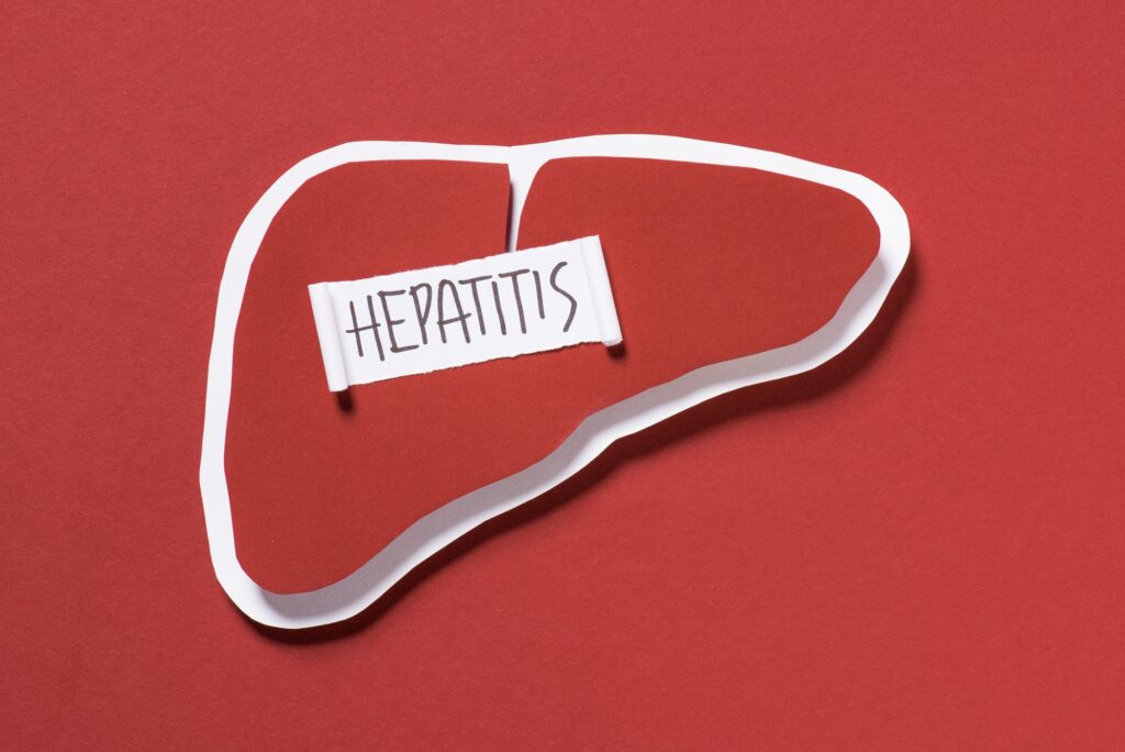 top view of liver and lettering hepatitis on red background, world hepatitis day concept